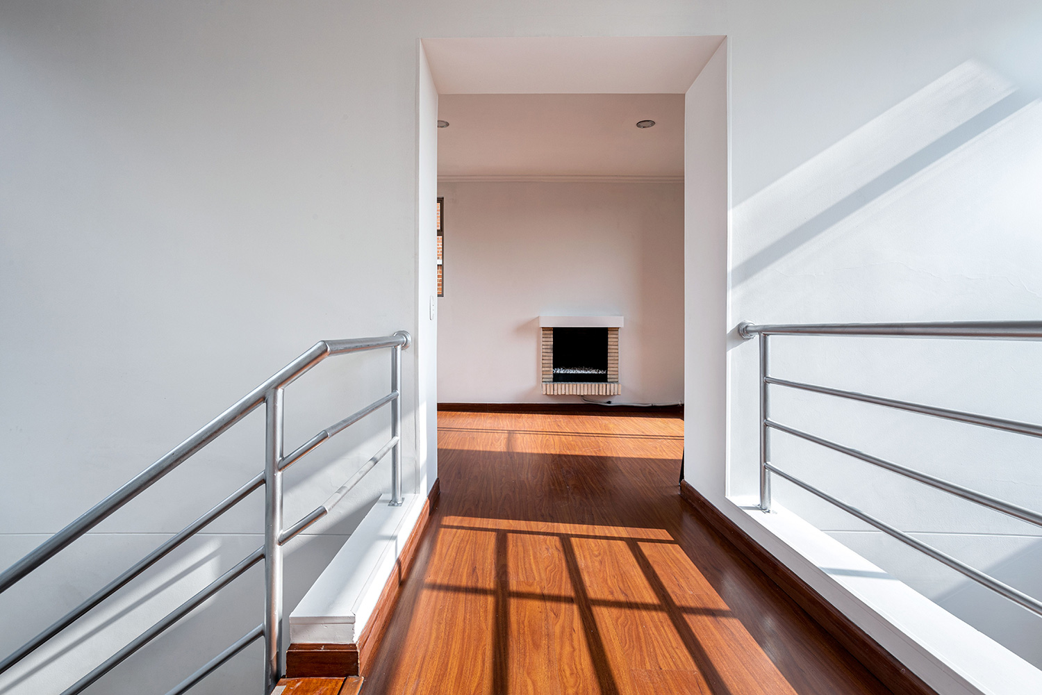 An image of an upstairs hallway, leading to an open space.