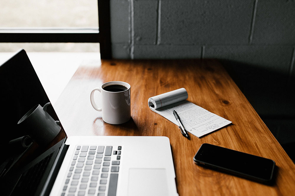 An image of a desk with a laptop and notes.